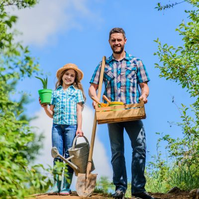 Green life. farmer man with little girl. garden tools, shovel and watering can. kid worker with dad hold box. family bonding. spring country side village. father & daughter on rancho. summer farming.